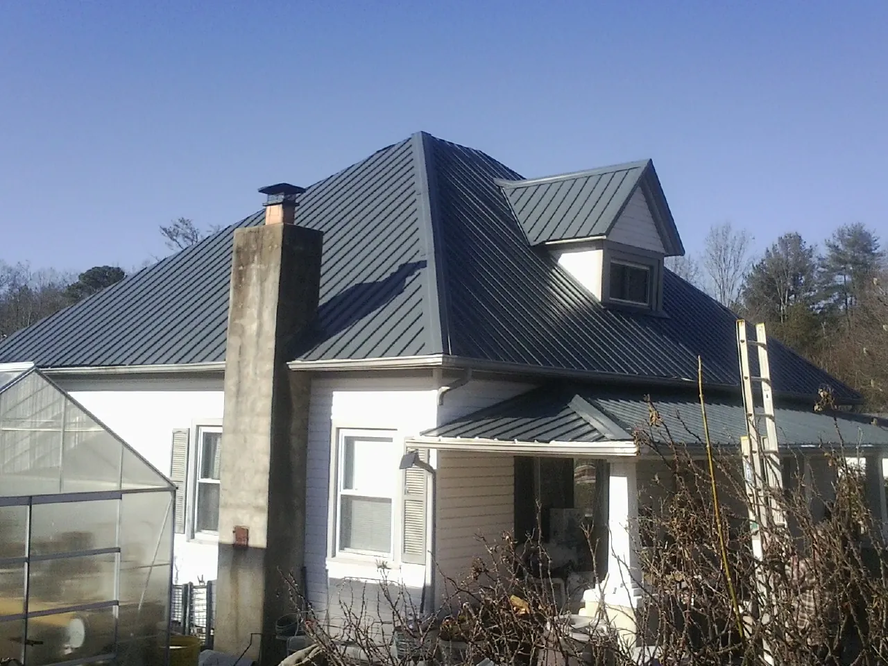 Dark blue standing seam metal roof on a white farmhouse with dormer — Slate & Tile Roof Repair by Roofing Brothers in Savannah