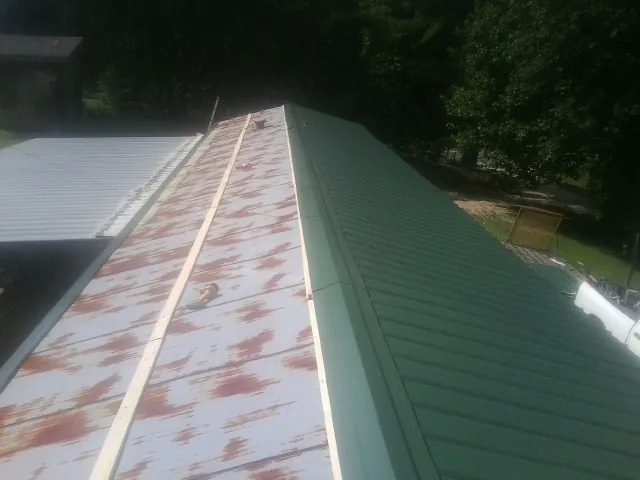 Old rusted panels beside newly installed green metal roofing — Wind Damage Roof Repair by Roofing Brothers in Savannah