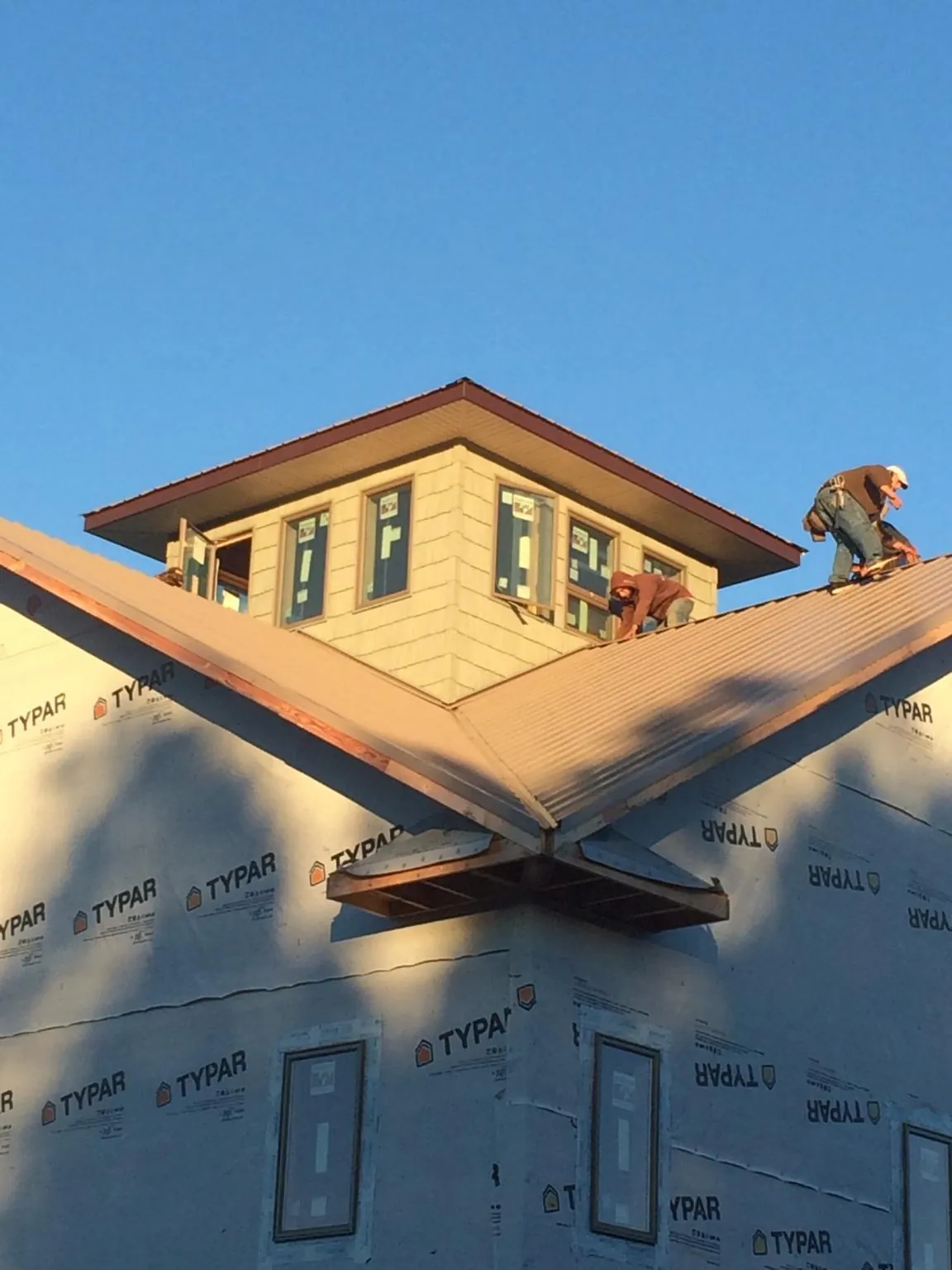Roofers working around a rooftop cupola on a new metal roof at sunset — Roof Waterproofing in Savannah by Roofing Brothers